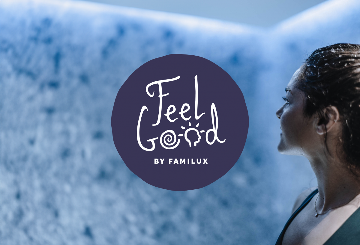 Dunkelblaues, rundes Feel Good Logo by Familux, rechts davon das Gesicht einer Frau.