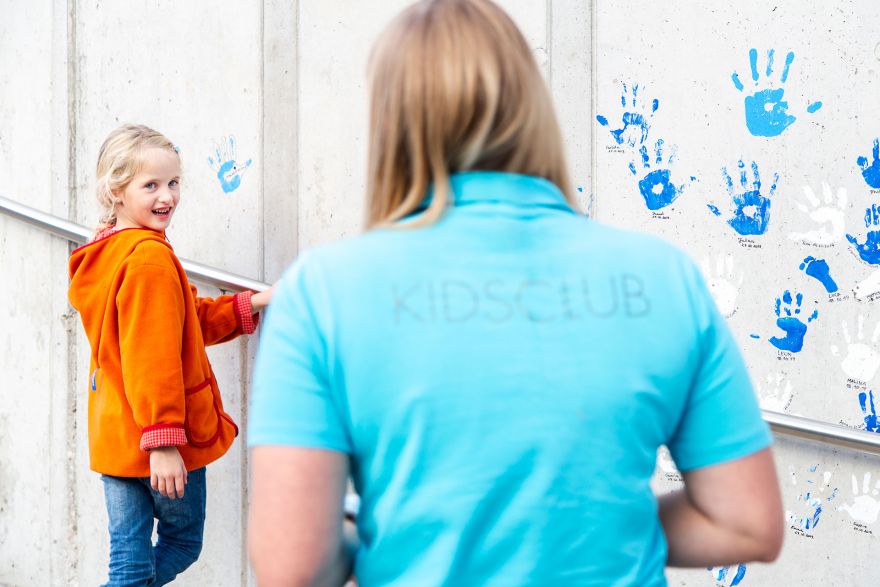 A woman from the kids' club with her back to the camera is smiled at by a young girl.