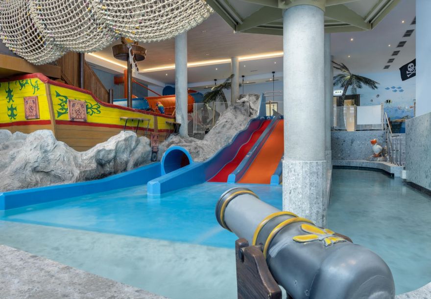 Indoor water playground for children with water slides and a large pirate ship.