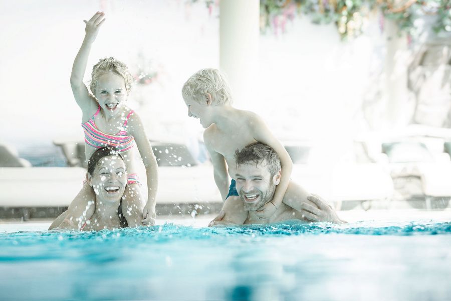Eine Familie hat Spaß im Pool, die Tochter auf den Schultern der Mutter, der Sohn beim Vater. Eine Familie hat Spaß im Pool, die Tochter auf den Schultern der Mutter, der Sohn beim Vater.