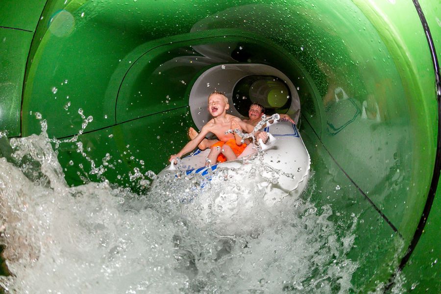 Blick in eine Wasserrutsche, auf der zwei Kinder in einem Schlauchboot rutschen. Blick in eine Wasserrutsche, auf der zwei Kinder in einem Schlauchboot rutschen.