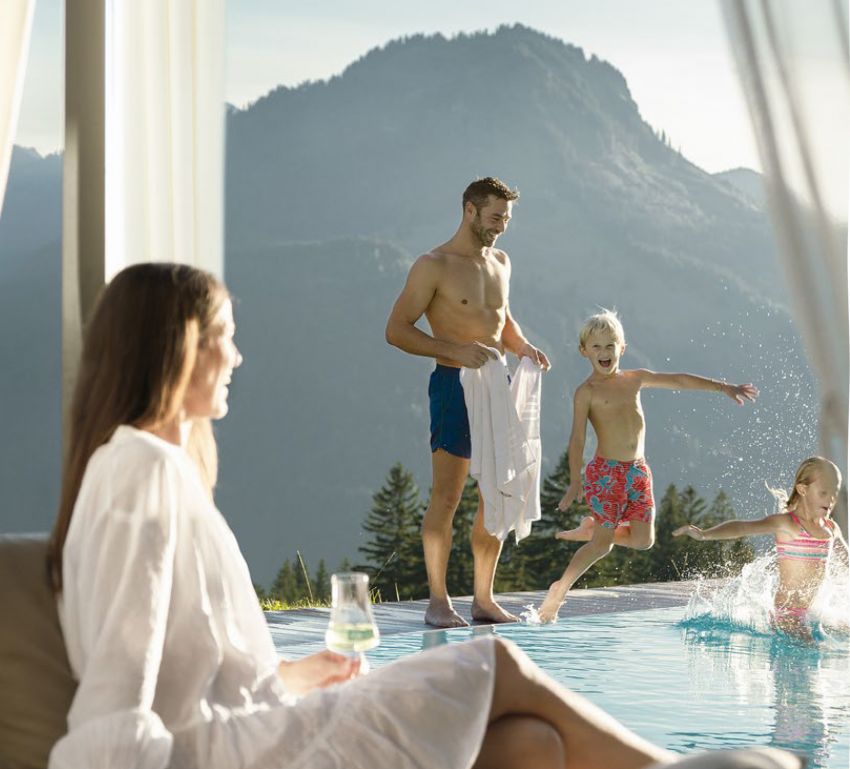 A happy family spends time together by the outdoor pool.