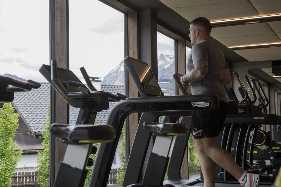 A person is running on a treadmill, with a view of the Zugspitze massif in the background A person is running on a treadmill, with a view of the Zugspitze massif in the background
