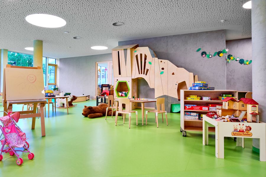 Bright room for children with numerous toys, a climbing structure, and light green flooring. Bright room for children with numerous toys, a climbing structure, and light green flooring.
