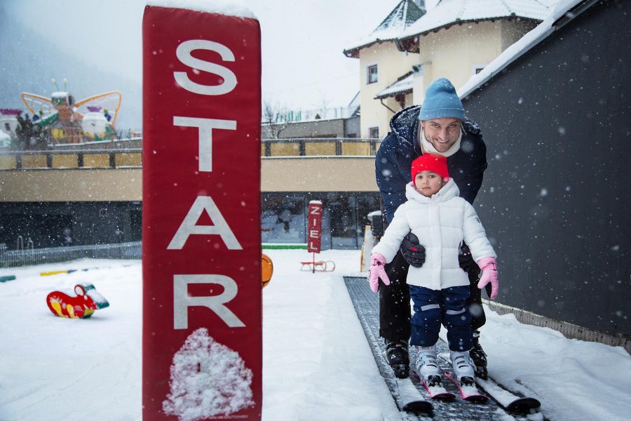 A smiling father is teaching his young child to ski in the snow. A smiling father is teaching his young child to ski in the snow.