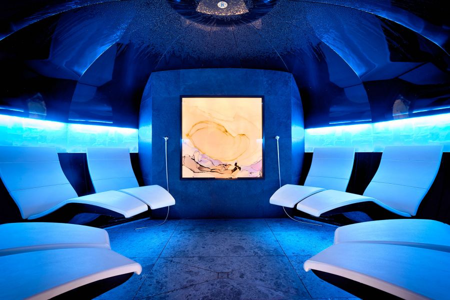 Dimly lit wellness area with blue lighting and eight loungers for relaxation. Dimly lit wellness area with blue lighting and eight loungers for relaxation.
